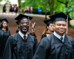 photo shows a crowd of smiling graduates wearing caps and gowns