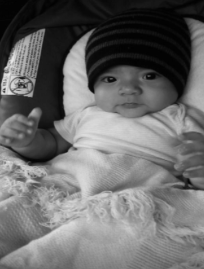 black-and-white photo of a happy baby wearing a stocking cap