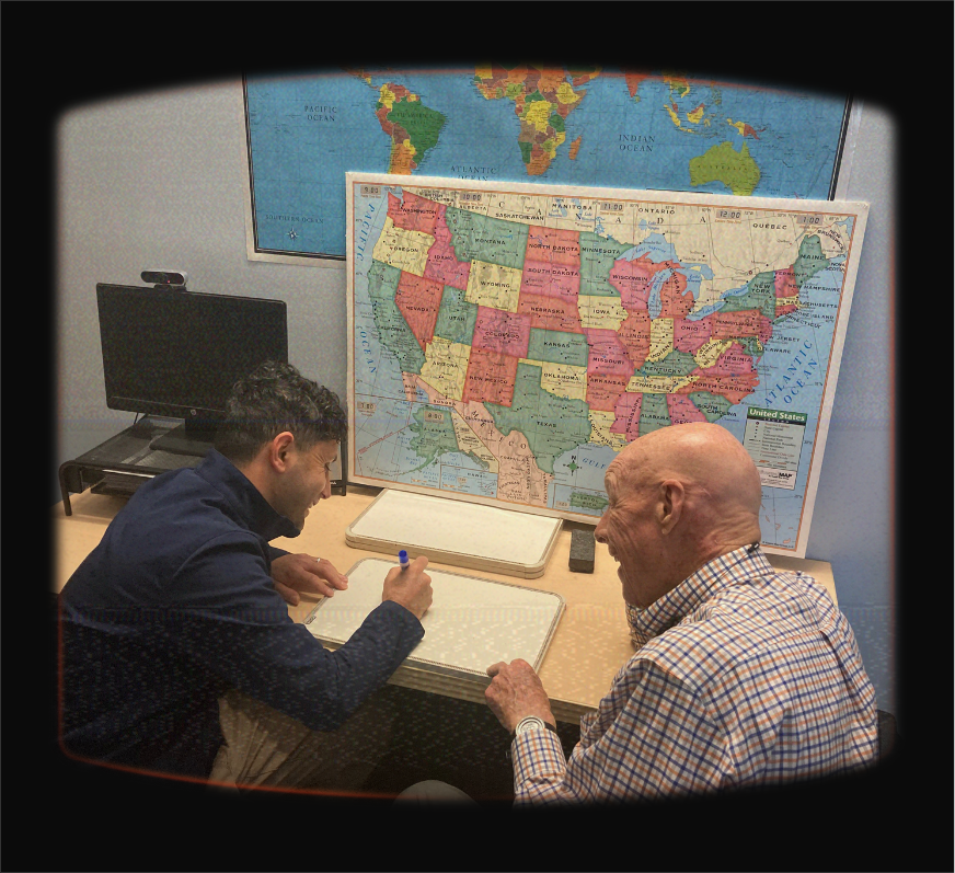 LVCA learner and tutor working at a desk in front of a map of the U.S. and the world
