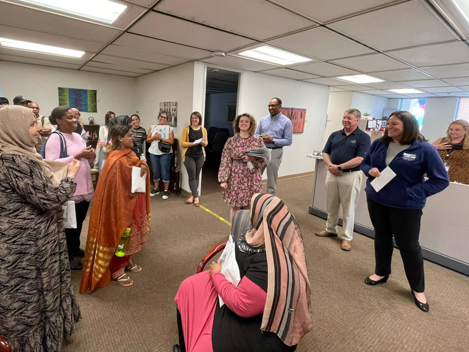 photograph shows a group of Blue Ridge Literacy learners, including many women wearing colorful shawls and head scarfs, as well as administrators. Both groups are smiling as the letter is presented.