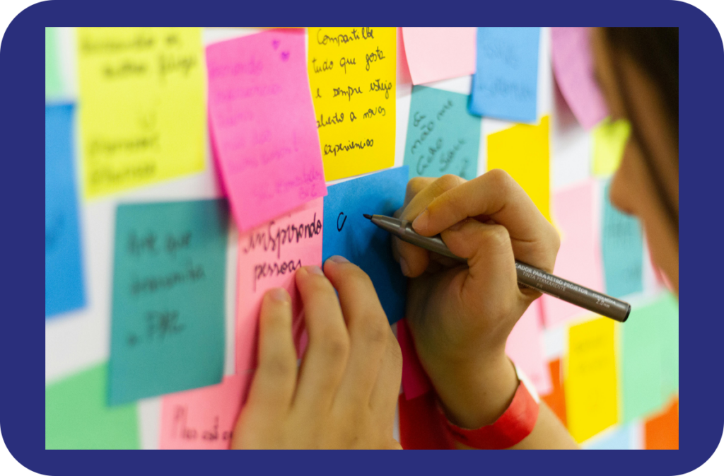 Closeup photo of hands writing on sticky notes posted on a wall