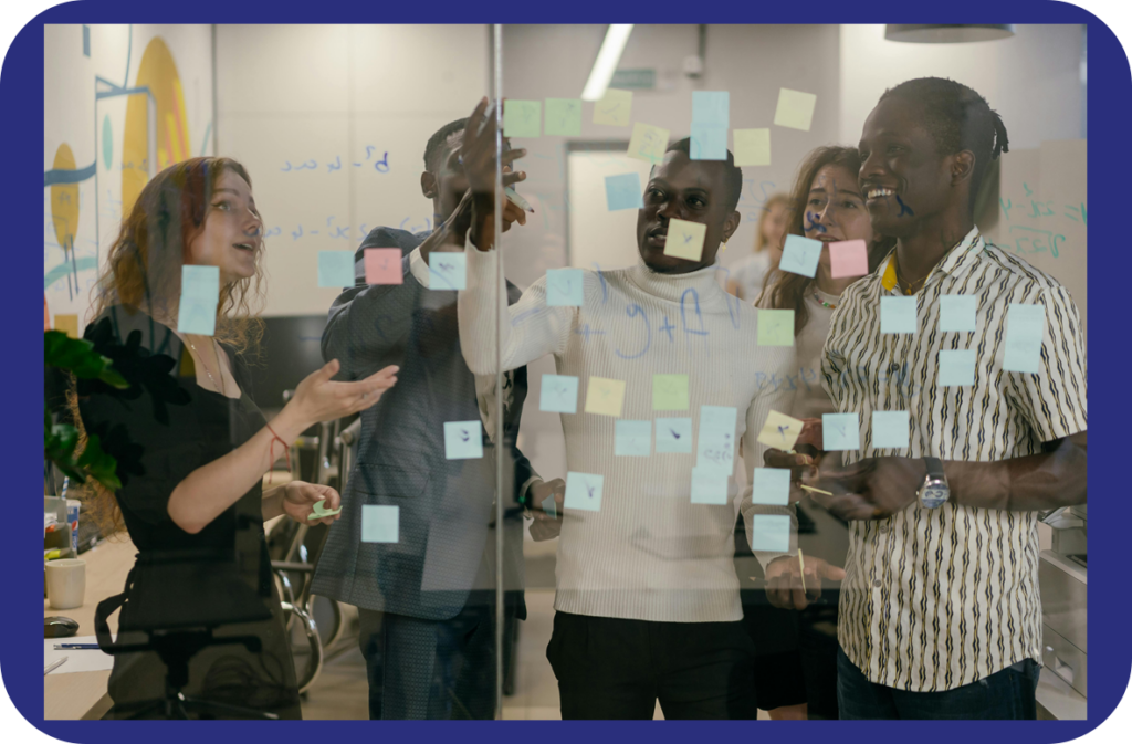 5 learners arranging sticky notes on a clear board