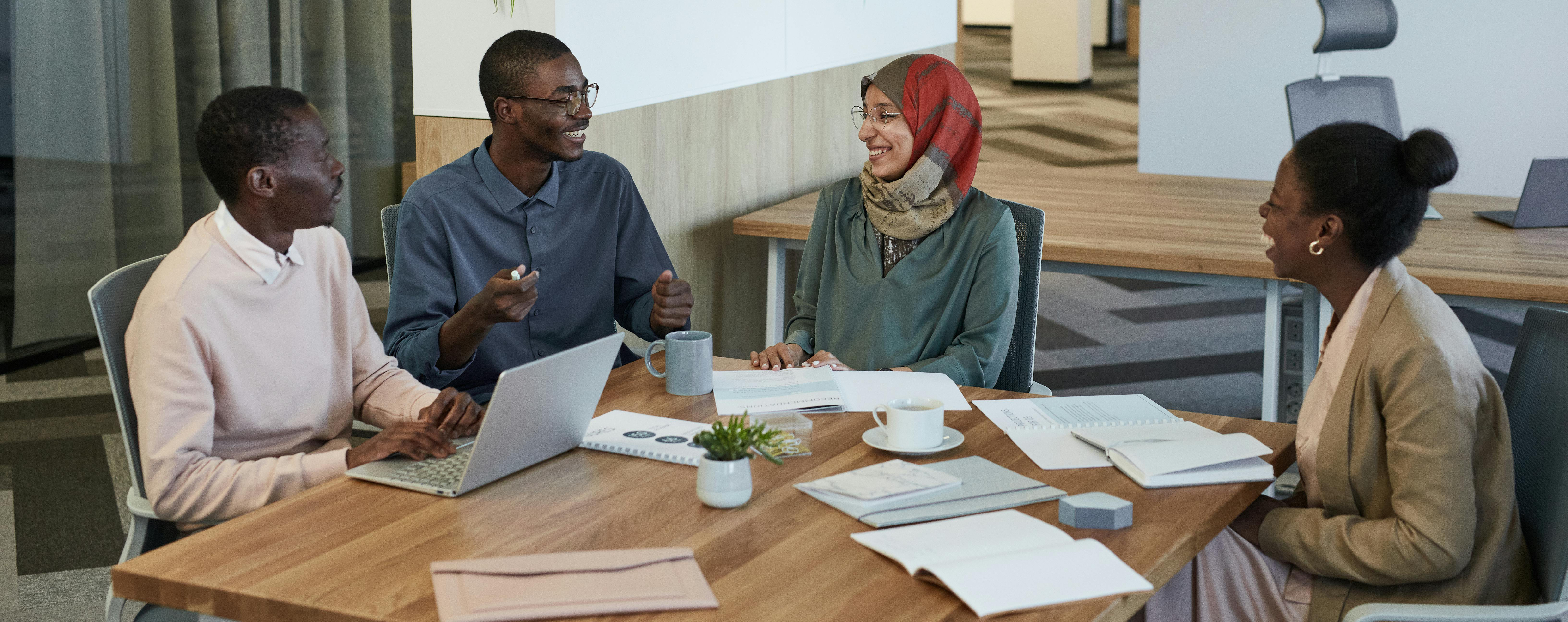 4 adult learners sitting around a table with a computer and papers