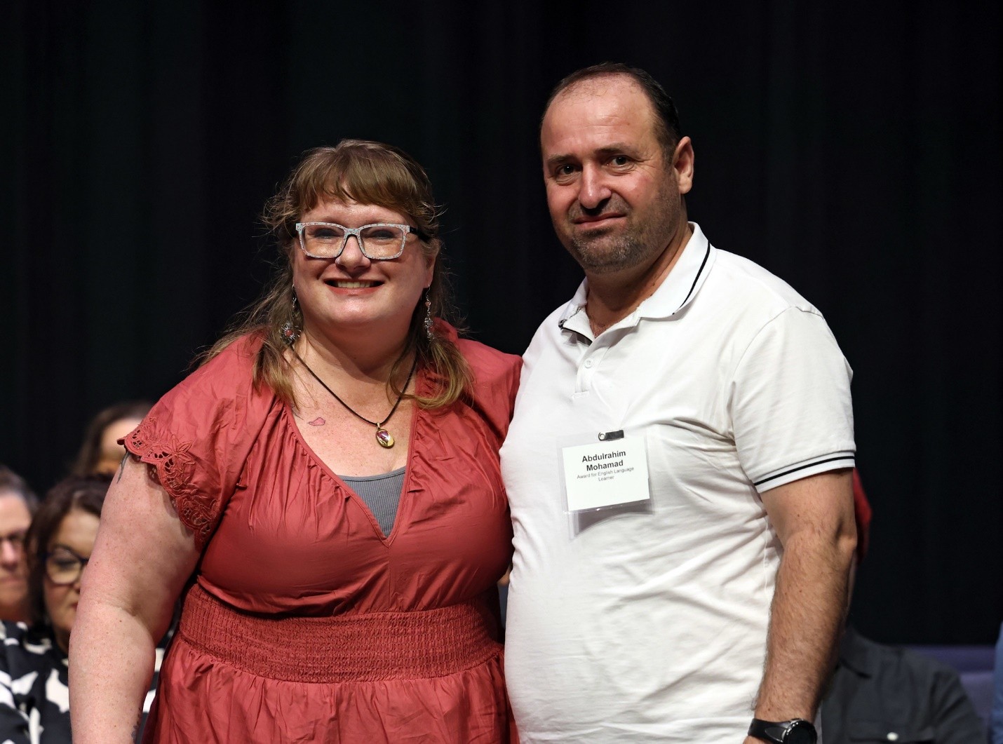 Academic awardee Abdulrahim Mohamad smiles modestly as he faces the camera; next to him is his beaming teacher, Cherry Stewart