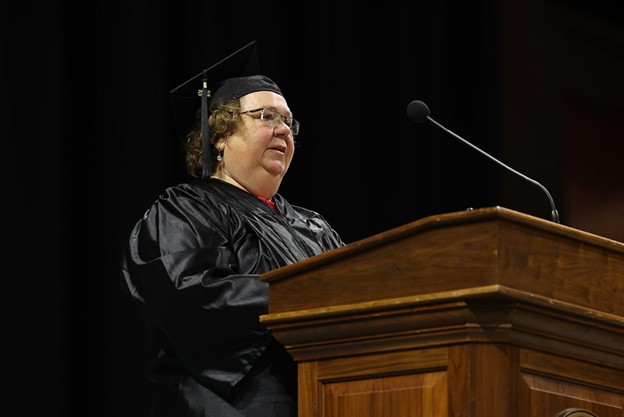 photograph of Sally Carr, in cap and gown, speaking at the podium during PVCC commencement